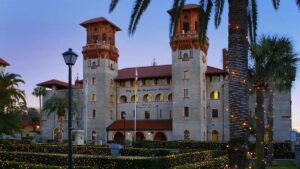 Exterior shot of old spanish style stone building and dusk with palm trees and shrubbery covered in lights
